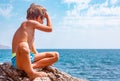 Boy on the beach stones. against the background of clear sea water