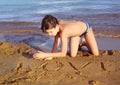 Boy on the beach take sun bathing play with sand