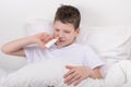 The boy is in bed, his nose is stuffy, he takes the medicine nasally Royalty Free Stock Photo