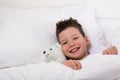 Boy in bed under a blanket with toy smiling Royalty Free Stock Photo