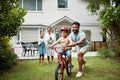 Boy on bicycle learning with proud dad and happy family in their home garden outdoors. Smiling father teaching fun skill Royalty Free Stock Photo