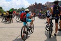 A boy with a big red backpack rides a bicycle down the street at a sports festival Bicycle Day. A group of cyclists, cycling