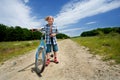 Boy with bike on a country road through meadow Royalty Free Stock Photo