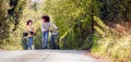 Boy With Bike And Girl With Skateboard Walking Along Country Road Together Royalty Free Stock Photo