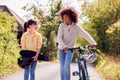 Boy With Bike And Girl With Skateboard Walking Along Country Road Together Royalty Free Stock Photo