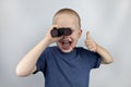 A boy with binoculars looks into the distance and smiles. Facial expression and body position show victory. The concept of vision