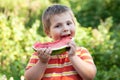 Boy bites off a piece of watermelon