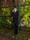 Boy in black suit said by telephone amid foliage