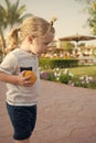 Boy with blond hair ponytail playing with orange