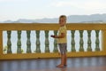 Boy, blonde hair, standing on the balcony, looking at the camera against background of the mountains, sea Royalty Free Stock Photo