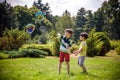 Boy blowing soap bubbles while an excited kid enjoys the bubbles. Happy teenage boy and his brother in a park enjoying making soap Royalty Free Stock Photo