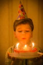 Boy blowing to burning candles at birthday cake Royalty Free Stock Photo