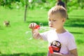 The boy blows bubbles in the park. Royalty Free Stock Photo