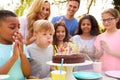 Boy Blows Out Candles As He Celebrates Birthday With Party For Parents And Friends In Garden At Home Royalty Free Stock Photo