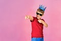 The boy in the blue crown on a pink background shows a finger forward