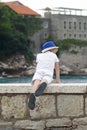 boy in a blue hat leaned over the parapet and looks thoughtfully