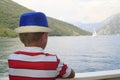 boy in a blue hat sails on a ferry across the Bay of Kotor and e