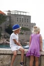 boy in a blue hat sits with his leg folded on a parapet and a gi