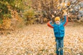 Boy in a blue jacket, scatters leaves in an autumn park. The child rejoices in the autumn leaves. Happy childhood. Bright yellow Royalty Free Stock Photo