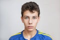 A boy in a blue shirt with dark hair on a gray background. Portrait of a sad boy Royalty Free Stock Photo