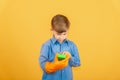 A boy in a blue shirt and orange gloves examines a green washing sponge Royalty Free Stock Photo