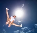 Boy, blue sky and jump outdoor with low angle, energy and lens flare of sunshine. Young teenager, below and leap in air