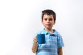 A boy in a blue T-shirt drinks with a blue cup stands on a light background Royalty Free Stock Photo