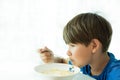 A boy in a blue T-shirt has breakfast with oatmeal and milk in a white plate, space for text, isolate