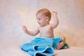 A boy in a blue towel sitting on a light background after a bath. Newborn baby resting in after bath or shower