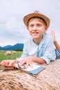 Boy with book lies on the hay roll