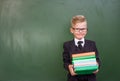 Boy with books standing near chalkboard