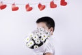 Boy with a bouquet of white flowers on a white background. red hearts on the background Royalty Free Stock Photo