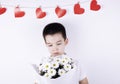 Boy with a bouquet of white flowers on a white background. red hearts on the background Royalty Free Stock Photo