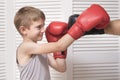 Boy in boxing gloves fights with a man`s hand in a glove. Royalty Free Stock Photo