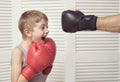 Boy in boxing gloves fights with a man`s hand in a glove. Royalty Free Stock Photo