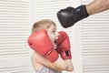 Boy in boxing gloves fights with a man`s hand in a glove. Royalty Free Stock Photo