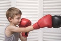 Boy in boxing gloves fights with a man`s hand in a glove. Royalty Free Stock Photo