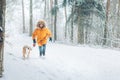 Boy in bright yellow parka walks with his beagle dog in snowy pine forest. Walking with pets and winter outfit concept image Royalty Free Stock Photo