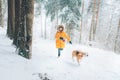 Boy in bright yellow parka walks with his beagle dog in snowy pine forest. Walking with pets and winter outfit concept image Royalty Free Stock Photo