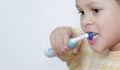 Boy brushing his teeth with an electric tooth brush stock image with grey background stock photo