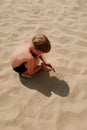 Boy building sandcastle on beach focus on hands. boy digs sand at sea shore, having fun on family summer vacation Royalty Free Stock Photo
