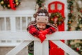 Boy in bull hat and red gloves posing up white fence and making funny faces Royalty Free Stock Photo
