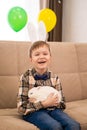 A boy in a bunny ears headband holds a white rabbit in his arms, smiles and looks at the camera. Easter Royalty Free Stock Photo