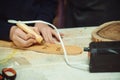 Boy burn out numbers with soldering iron on wooden disc. Kid makes wooden clock in the workshop Royalty Free Stock Photo