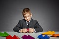 Boy in business suit making color paper planes