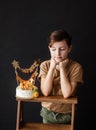 a boy with a cake, he has a birthday, a boy wearing a beige t-shirt and green pants on a black background Royalty Free Stock Photo