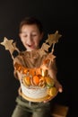 a boy with a cake, he has a birthday, a boy wearing a beige t-shirt and green pants on a black background Royalty Free Stock Photo