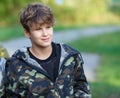 Boy in camouflage suit stands on the paintball field with his paintball gun up and looks straight ahead. team work, sport Royalty Free Stock Photo