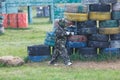 Boy in camouflage suit stands on the paintball field with his paintball gun up and looks straight ahead. team work, sport Royalty Free Stock Photo