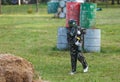 Boy in camouflage suit stands on the paintball field with his paintball gun up and looks straight ahead. team work, sport Royalty Free Stock Photo